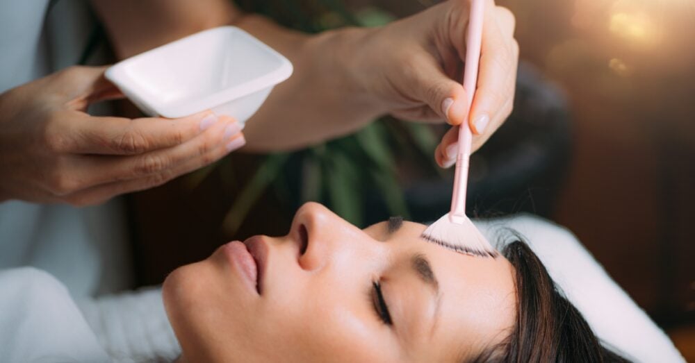 Aesthetician applying a chemical peel solution to a female’s face at a med spa