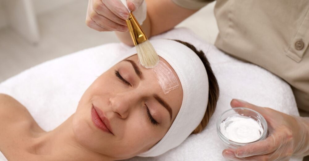 Provider applying a chemical peel treatment to reduce acne scars on a relaxed female