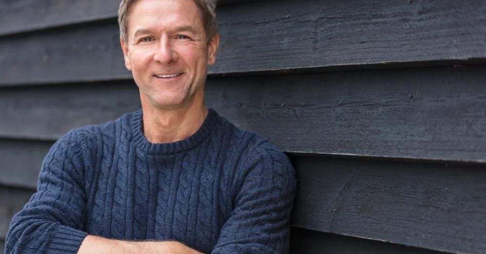 Middle aged man in a blue sweater smiling