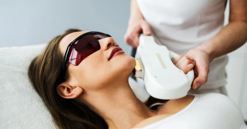 A woman wearing protective goggles receiving an IPL photofacial treatment