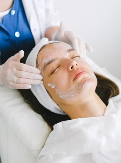 Esthetician applying a cream treatment to a patient’s face