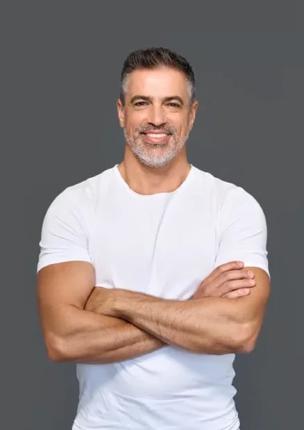 Smiling man with a salt-and-pepper beard in a white T-shirt, arms crossed