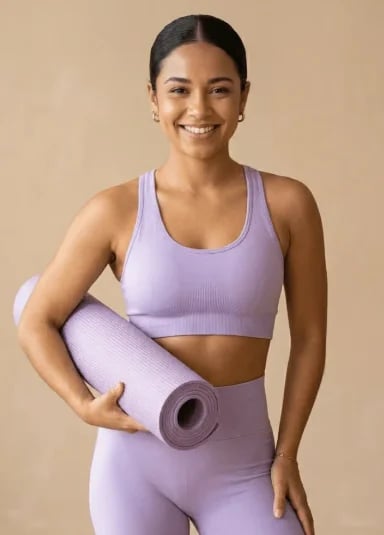 Smiling woman in lilac activewear holding a rolled yoga mat