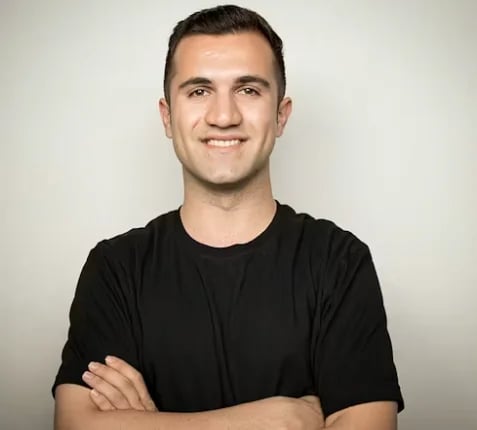 Smiling man in a black T-shirt standing with his arms crossed