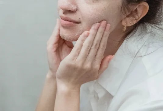 Woman gently cleansing her cheek with a foaming cleanser