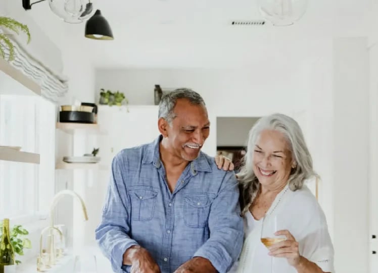 Smiling older couple standing together in a bright white kitchen